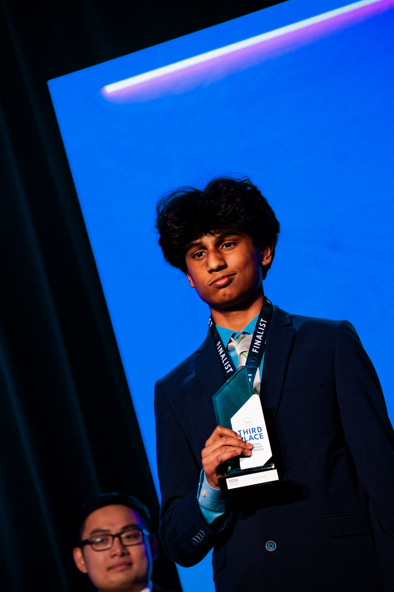 Young man in suit holding Third Place trophy — BPA National Leadership Conference