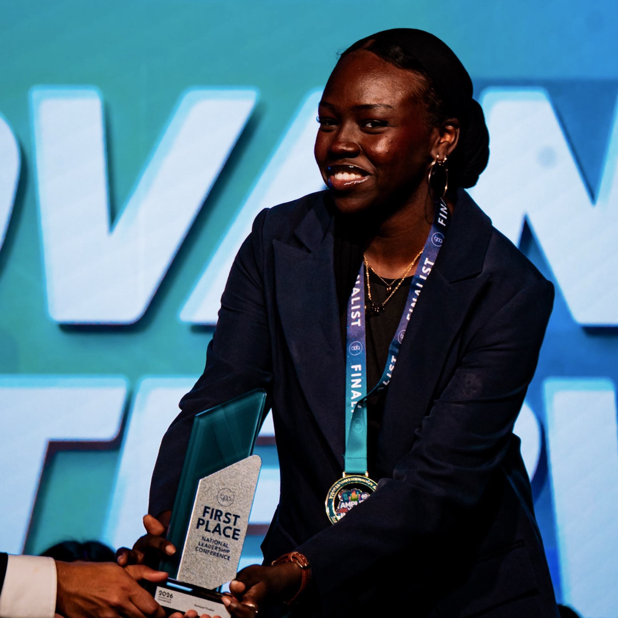 Woman in dark blue blazer accepting First Place trophy — BPA NLC