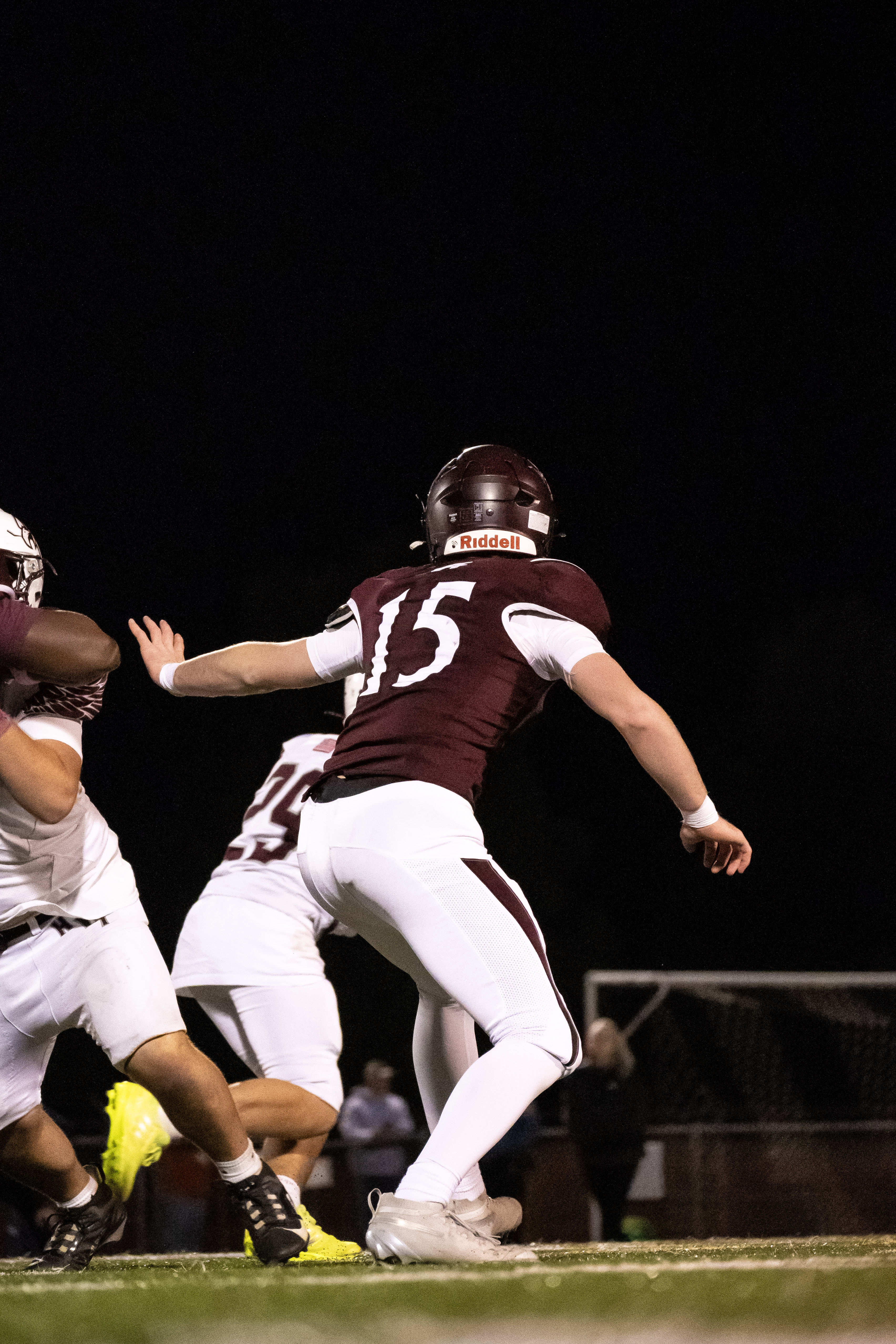 Football quarterback throwing at night under stadium lights