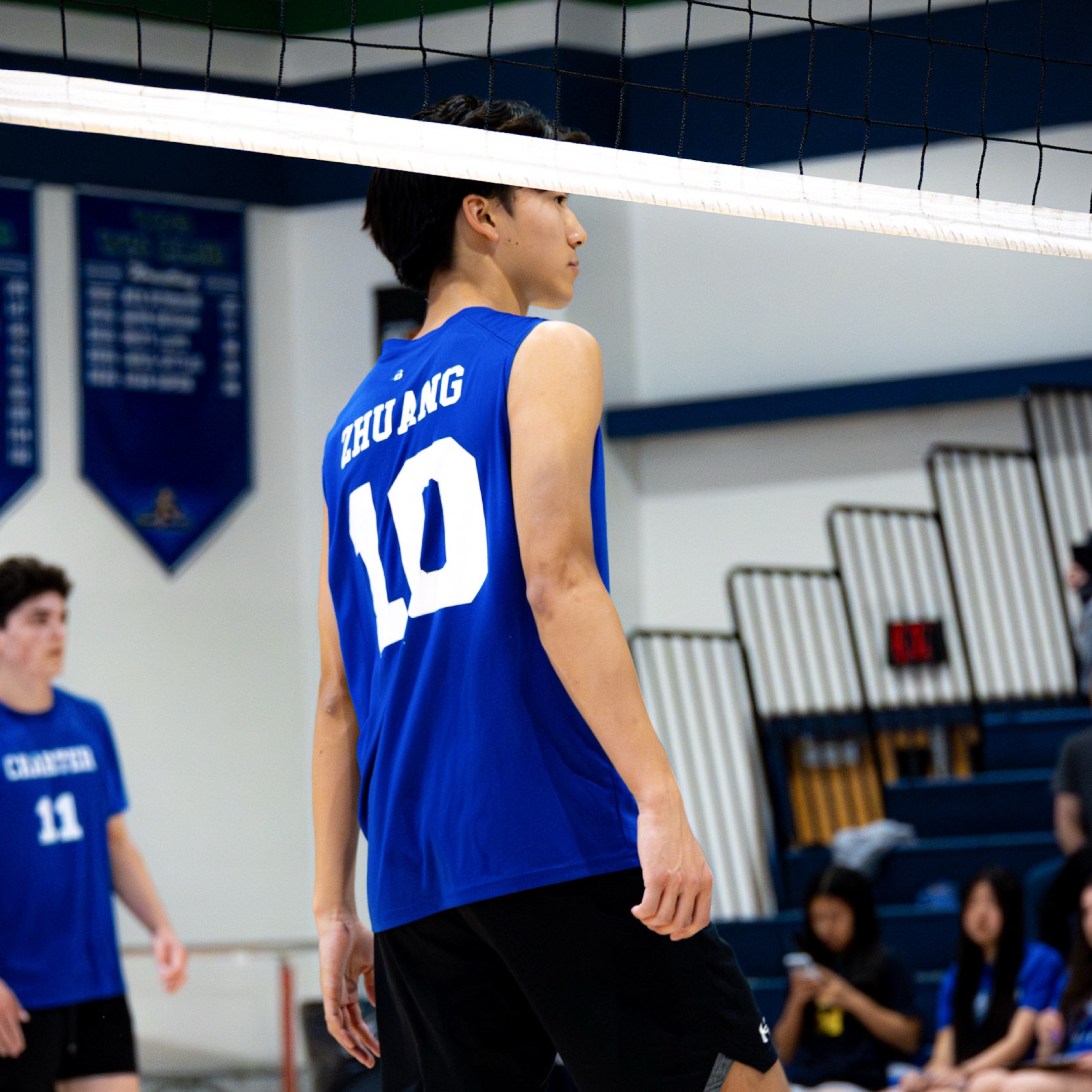 Volleyball player number 10 Zhuang standing near net, blue jersey
