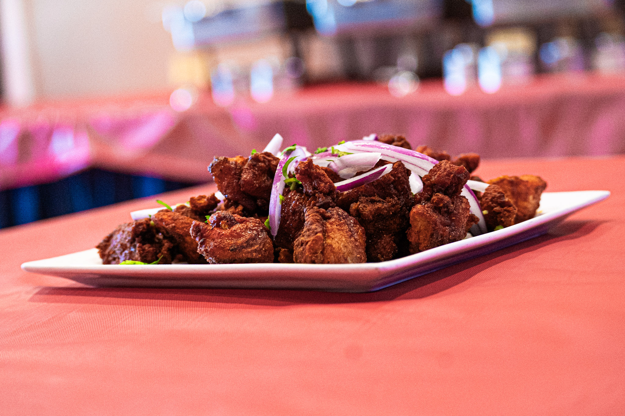 Pepper fry on white plate with red onion slices — AHA South Indian Cuisine